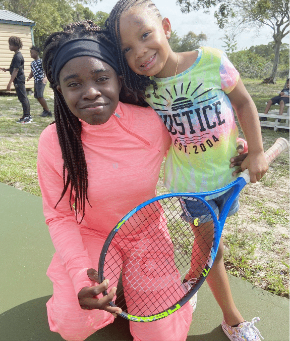 two young girls playing tennis